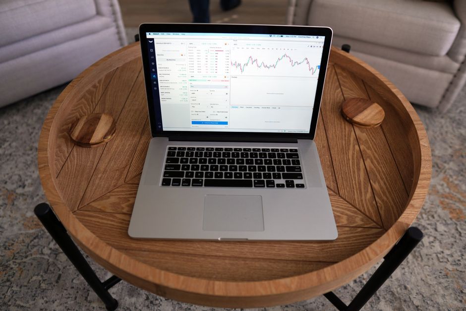 Laptop showing a financial chart on a wooden table