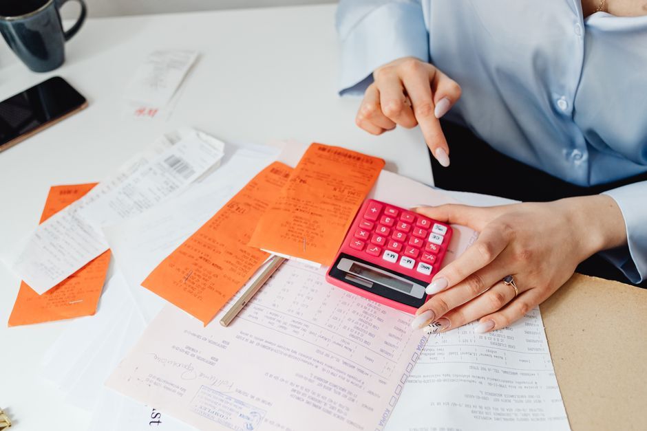 Receipts and a pink calculator on a desk during monthly bookkeeping